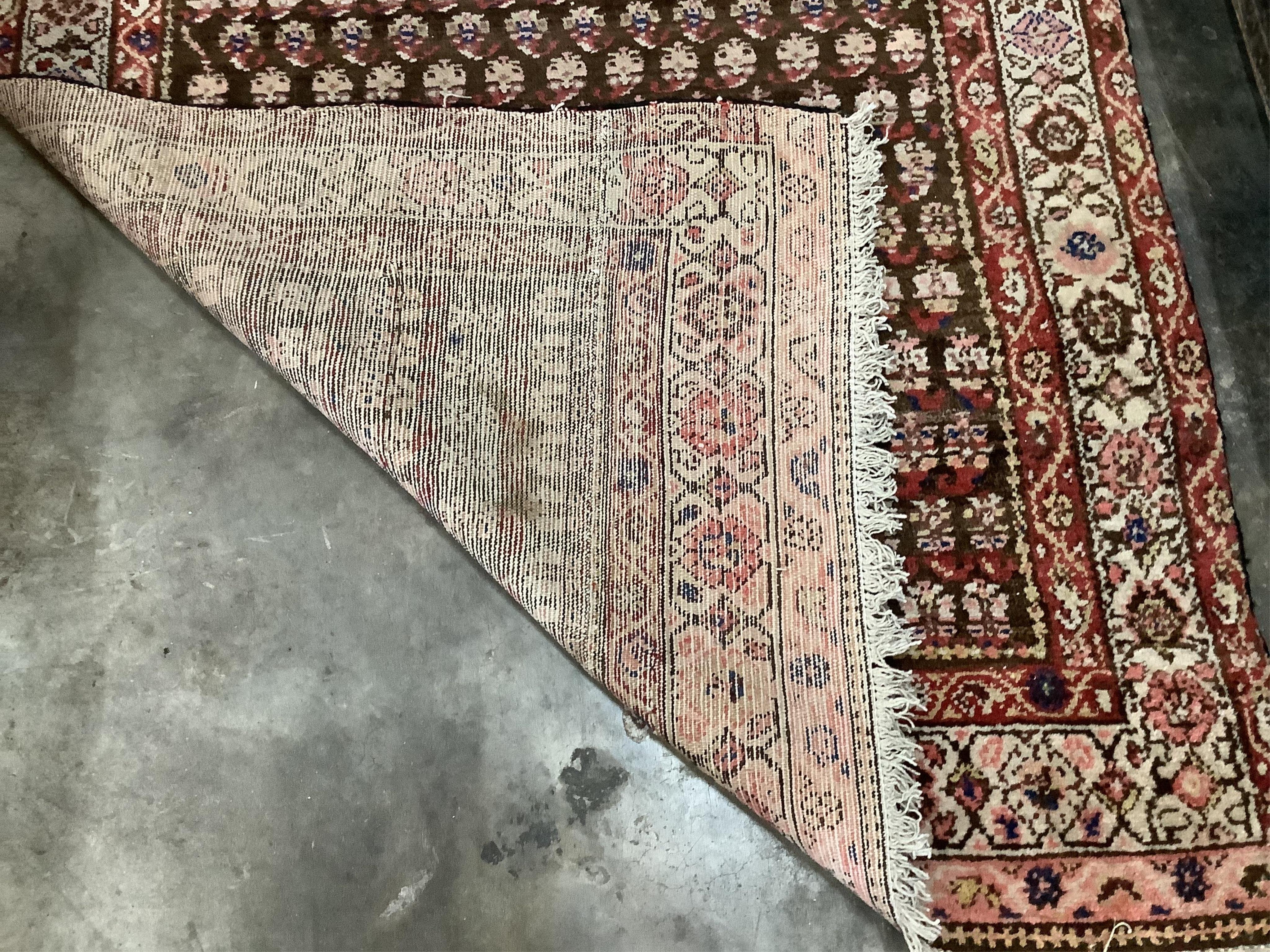 A Caucasian rug, woven with rows of botehs, on a burgundy ground, 202 x 104cm